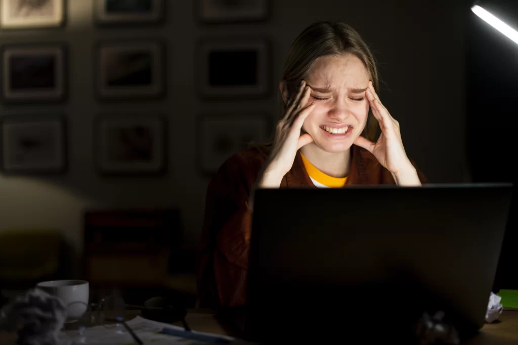 Mulher loira com expressão estressada olhando para o laptop, após cometer um erro — simboliza os desafios de ganhar dinheiro no TikTok com poucos seguidores.