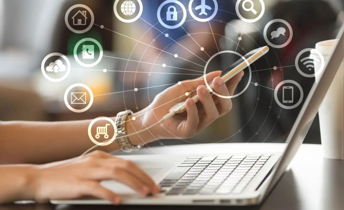 Pessoa utilizando smartphone e laptop com ícones digitais conectados, representando oportunidades no mercado digital
